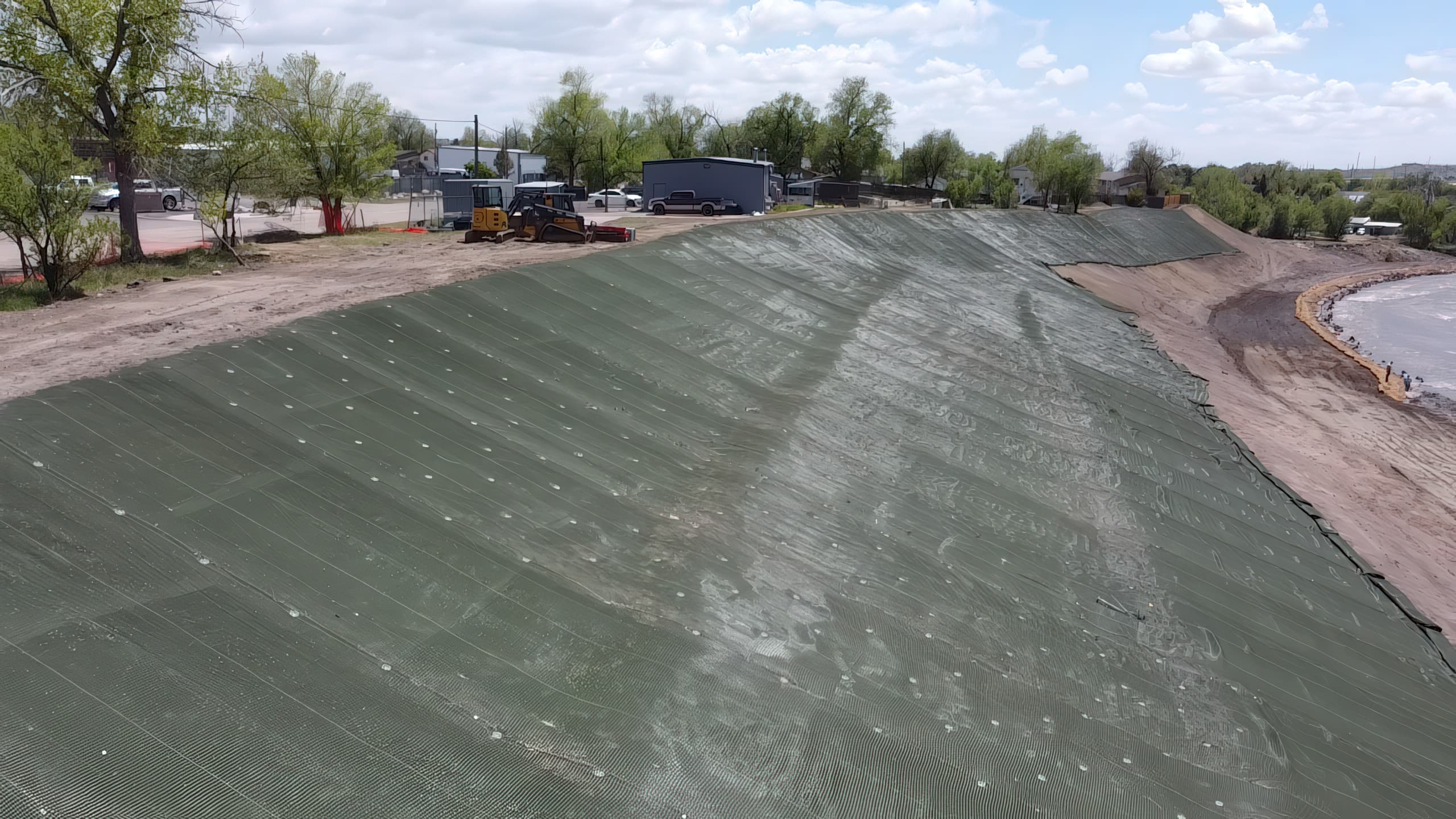 Crews securing PROPEX® Armormax® HPTRM with earth anchors to resist hydraulic forces and improve slope stability in the Southmoor Drive restoration project.